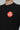 Close-up of the Black Red Shield Elite Mens Tee, highlighting the red Gracie Barra Red Shield emblem on the left chest against a light gray background.
