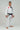 Adult athlete wearing the white GB1 Kimono in an angled front stance, showing the Red Shield chest patch, Gracie Barra lapel patch, reinforced jacket structure, and tapered performance fit.